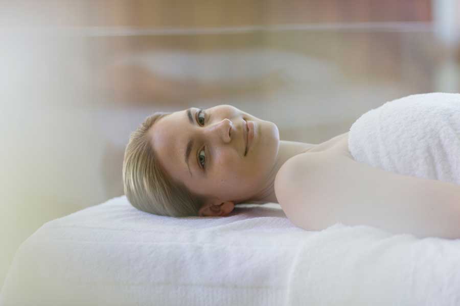 Portrait serene young woman relaxing on spa massage table 